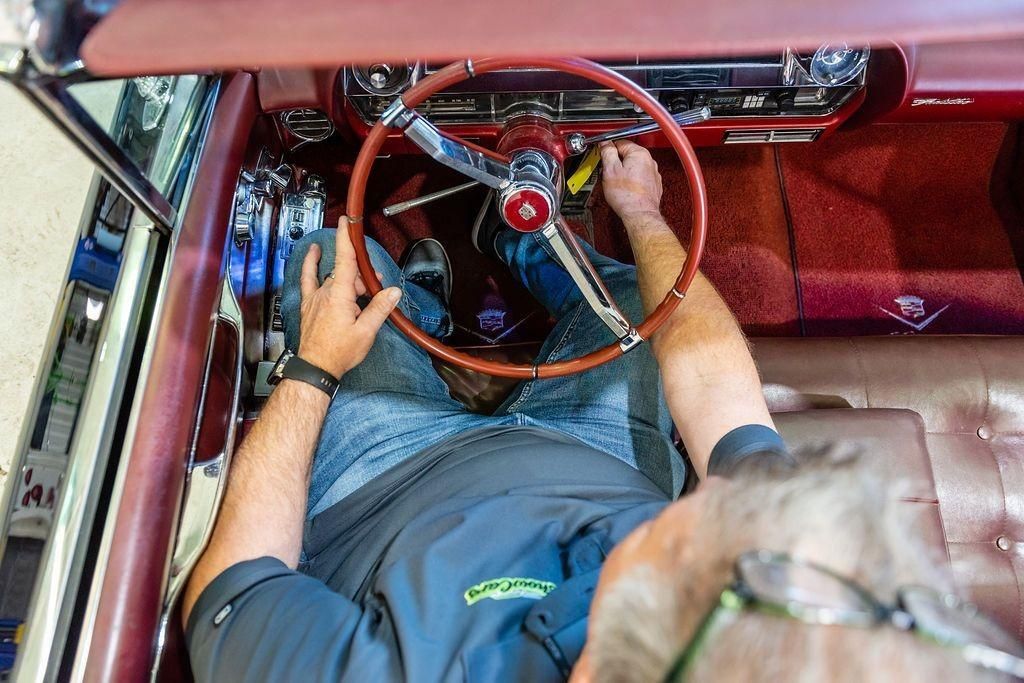 A man is working on the steering wheel of a car.