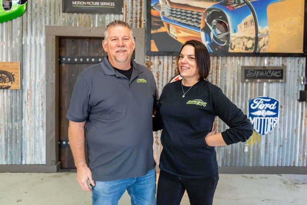 A man and a woman are posing for a picture in a garage.