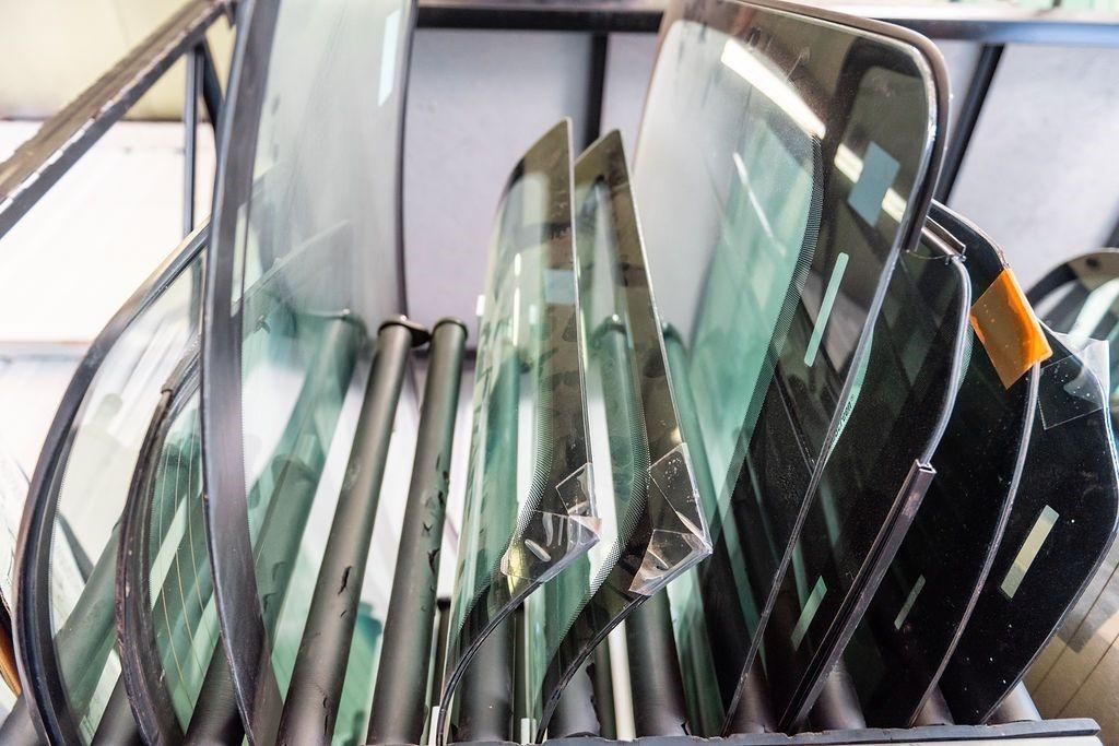 A bunch of windshields are stacked on top of each other on a rack.