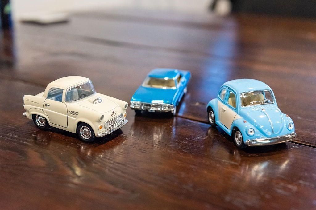 Three toy cars are sitting on a wooden table.