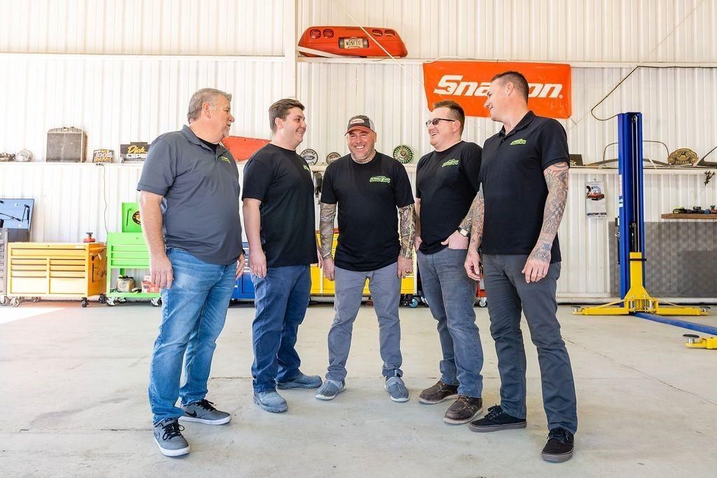 A group of men are standing next to each other in a garage.