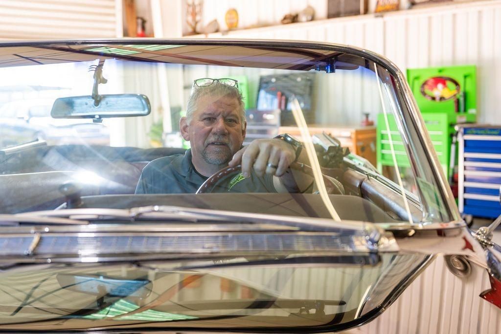 A man is looking through the windshield of a car in a garage.