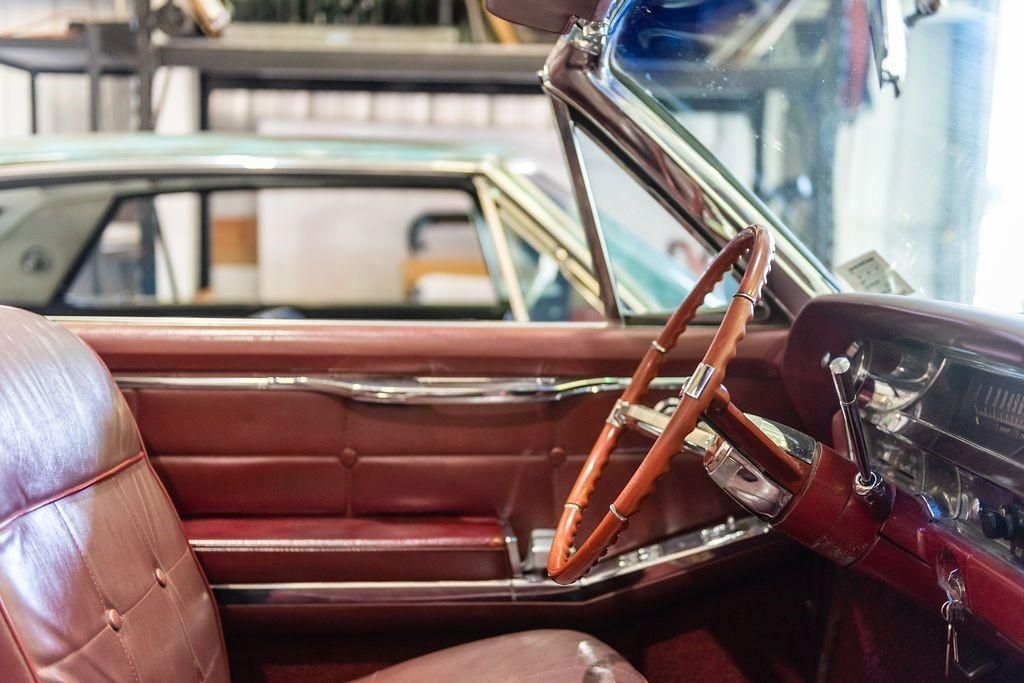 The inside of an old car with a wooden steering wheel.