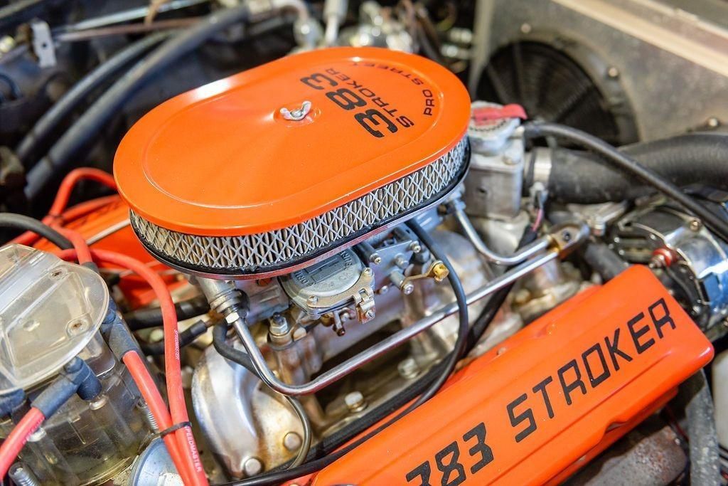 A close up of a car engine with an orange air filter.
