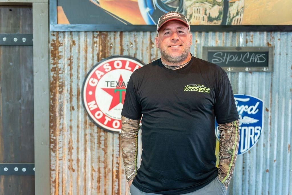 A man is standing in front of a wall with signs on it.