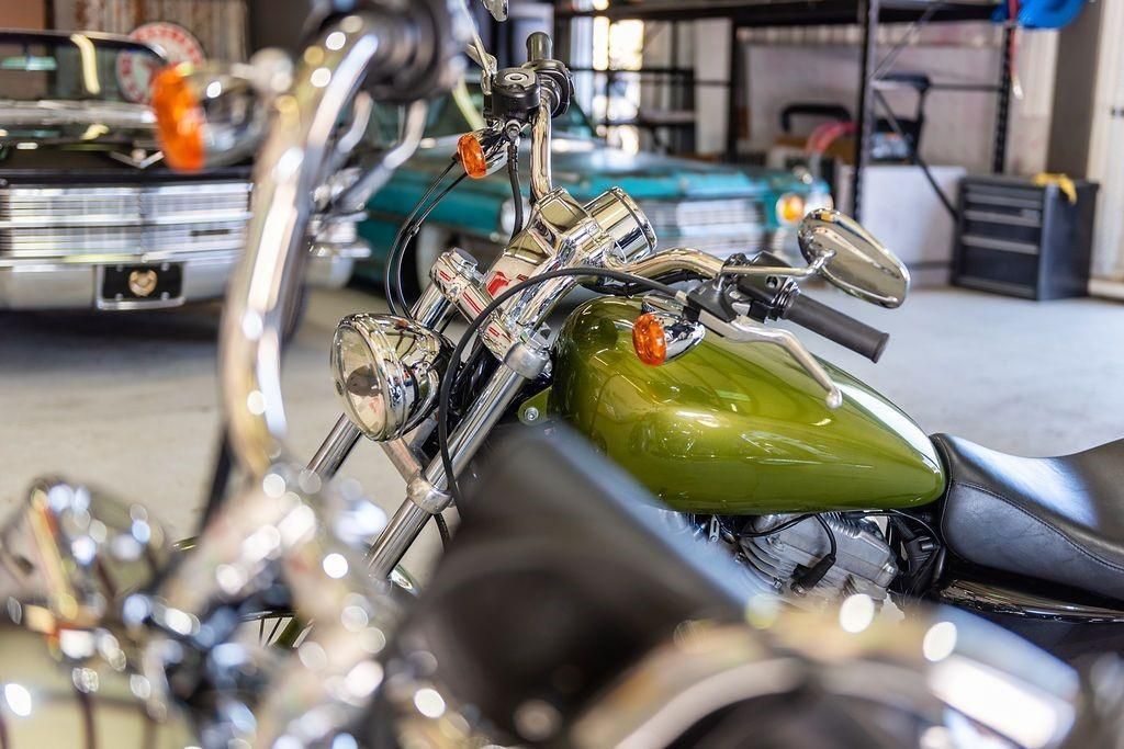 A motorcycle is parked in a garage next to a car.