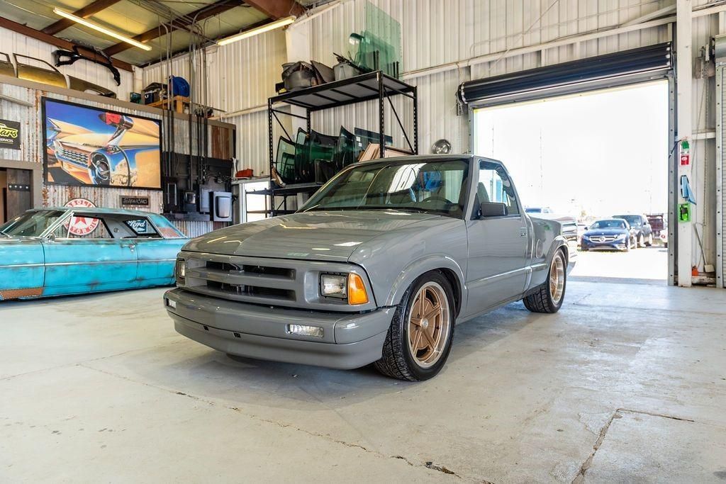 A gray truck is parked in a garage with a garage door open.