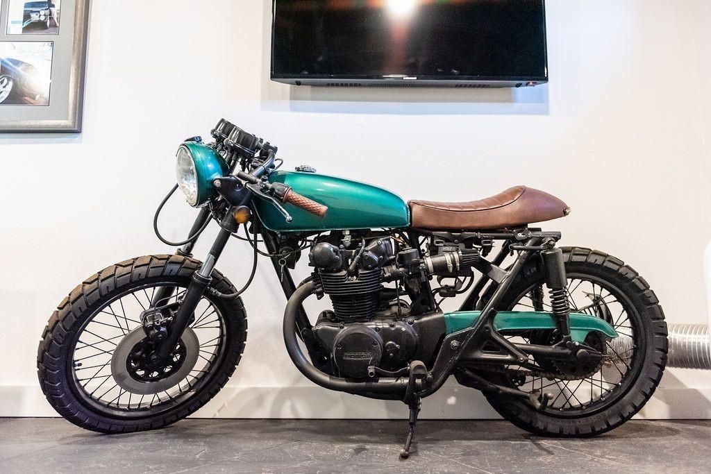 A green motorcycle is parked next to a wall in a room.