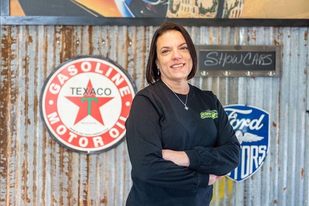 A woman is standing in front of a sign that says gasoline motor oil.