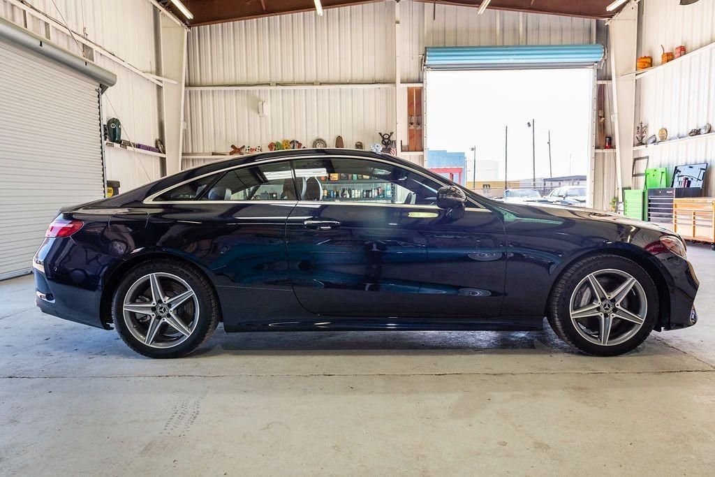 A black car is parked in a garage with a garage door open.