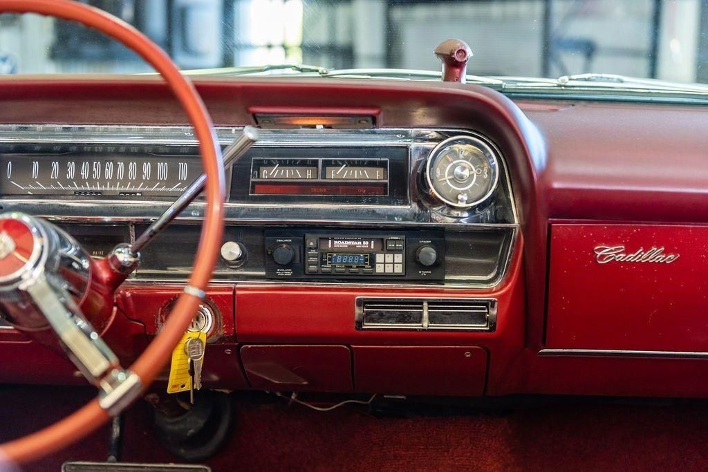 The interior of an old red cadillac with a steering wheel