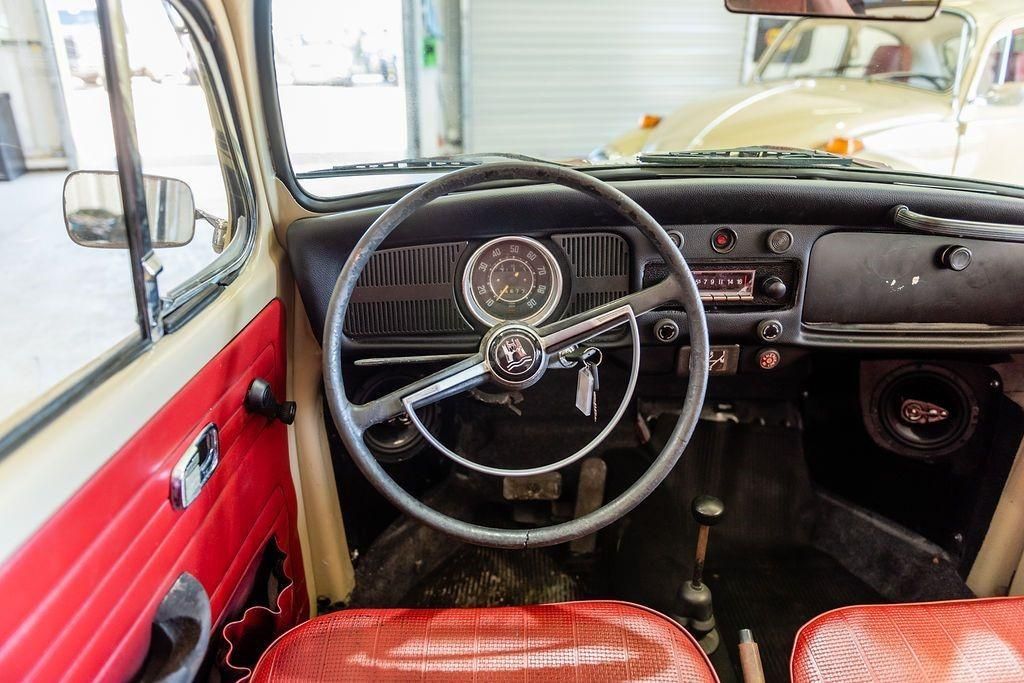 The interior of an old car with red seats and a steering wheel.