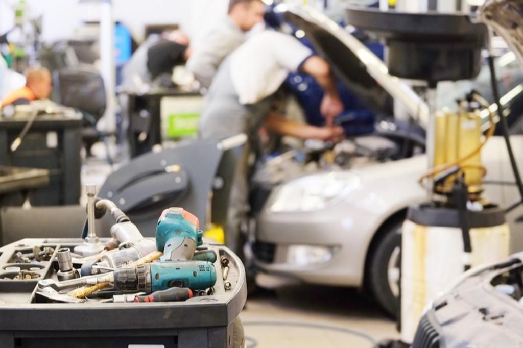 A car is being worked on in a garage with the hood open.