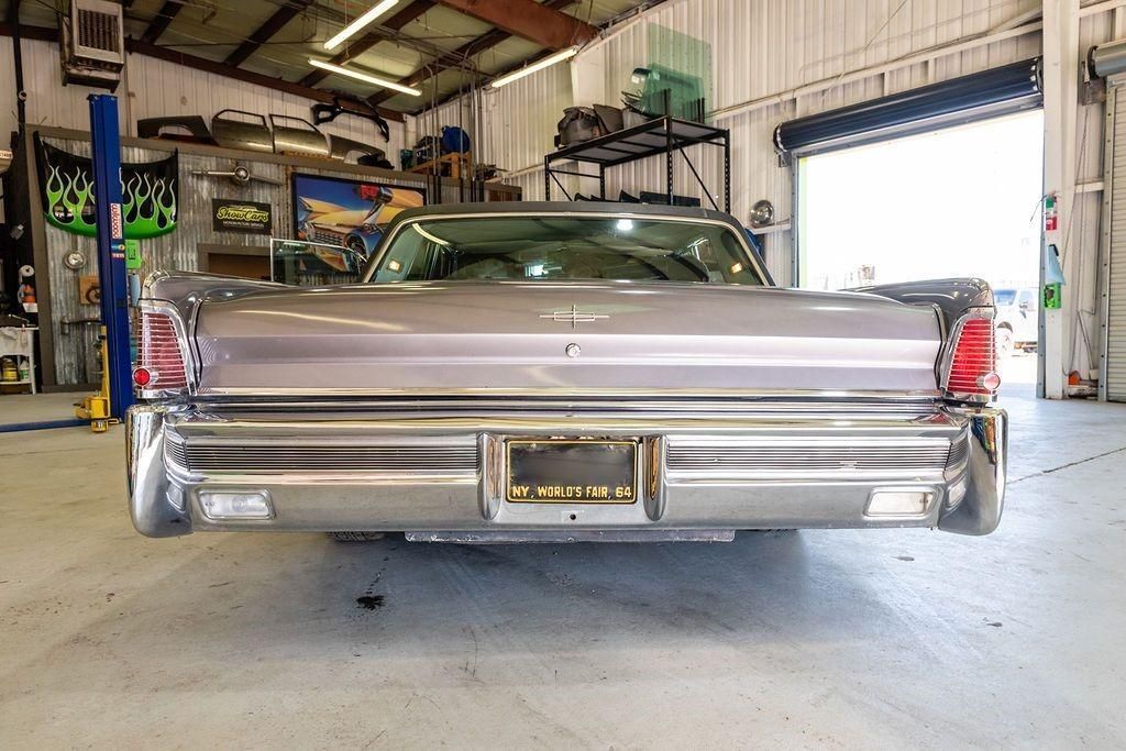 A silver car is parked in a garage next to a garage door.