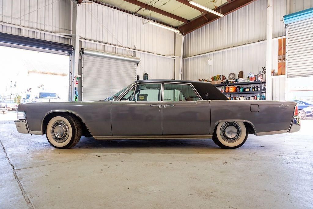 A gray lincoln continental is parked in a garage.