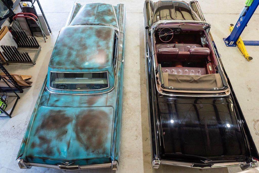 Two old cars are parked next to each other in a garage.