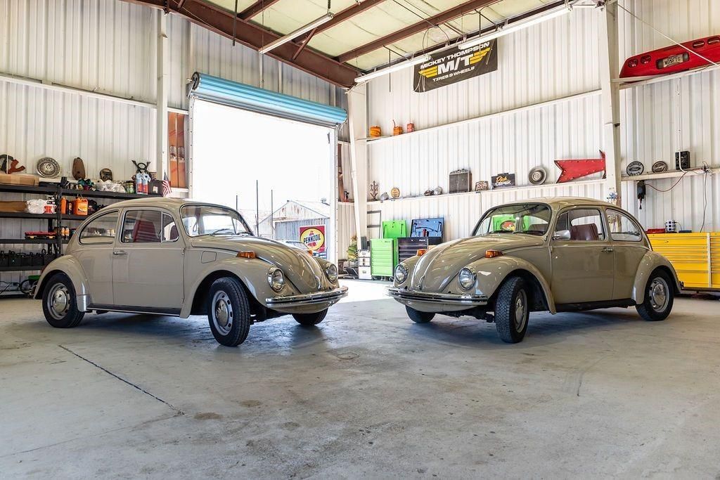 Two old cars are parked next to each other in a garage.