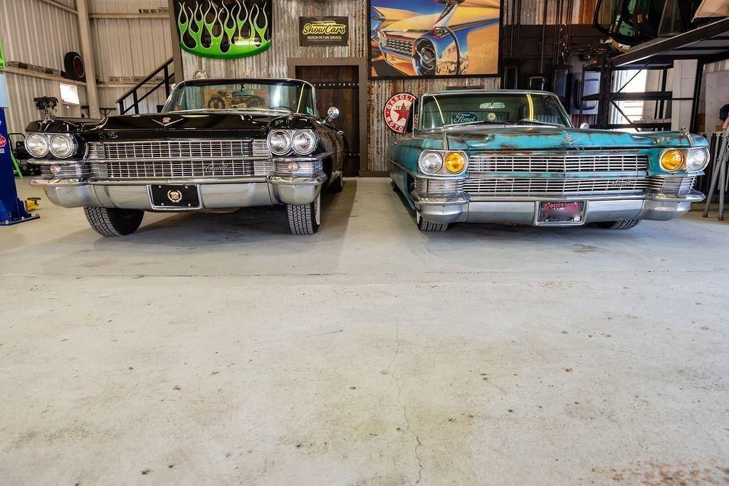 Two old cars are parked next to each other in a garage.