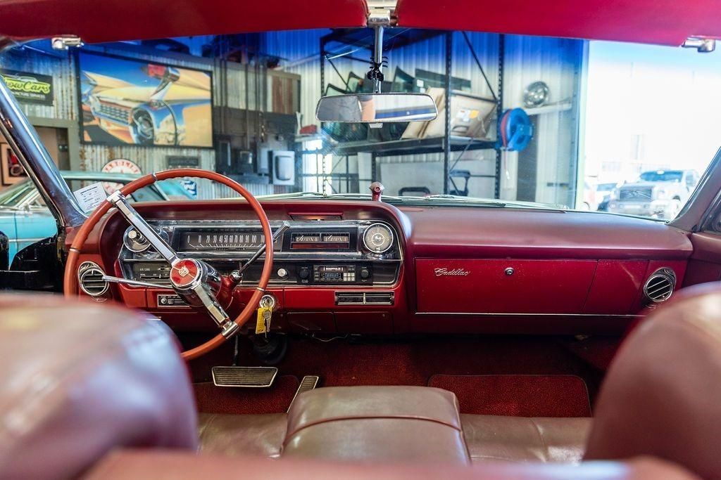 The interior of a red car with a steering wheel and dashboard.