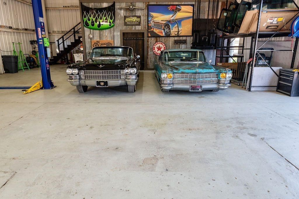 Two cars are parked in a garage next to each other.