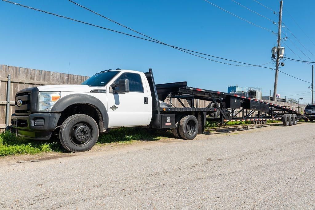 A white truck with a trailer attached to it is parked on the side of the road.