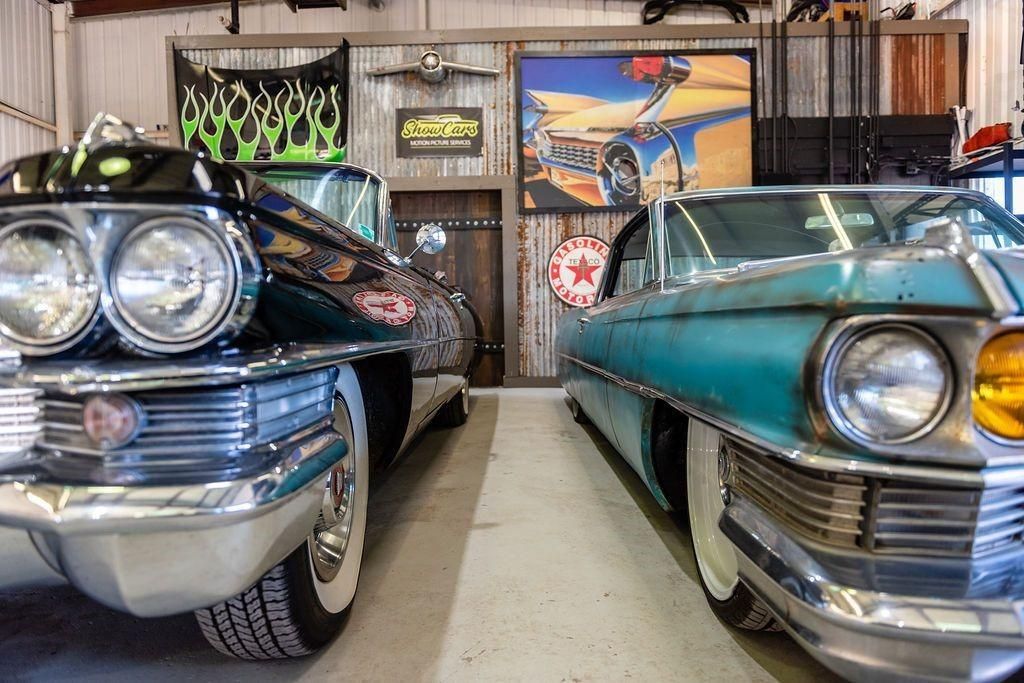 Two old cars are parked next to each other in a garage.
