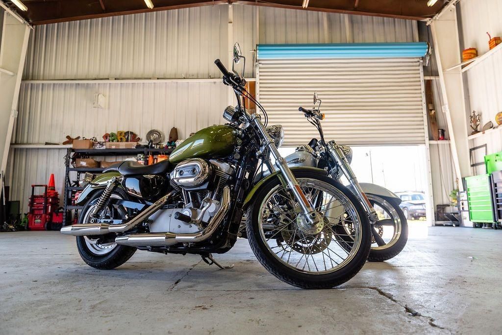 Two motorcycles are parked in a garage next to each other.