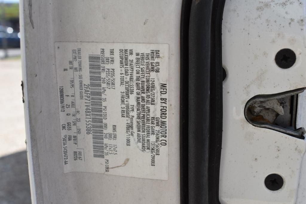 A white car with a sticker on the door that says ' ford ' on it