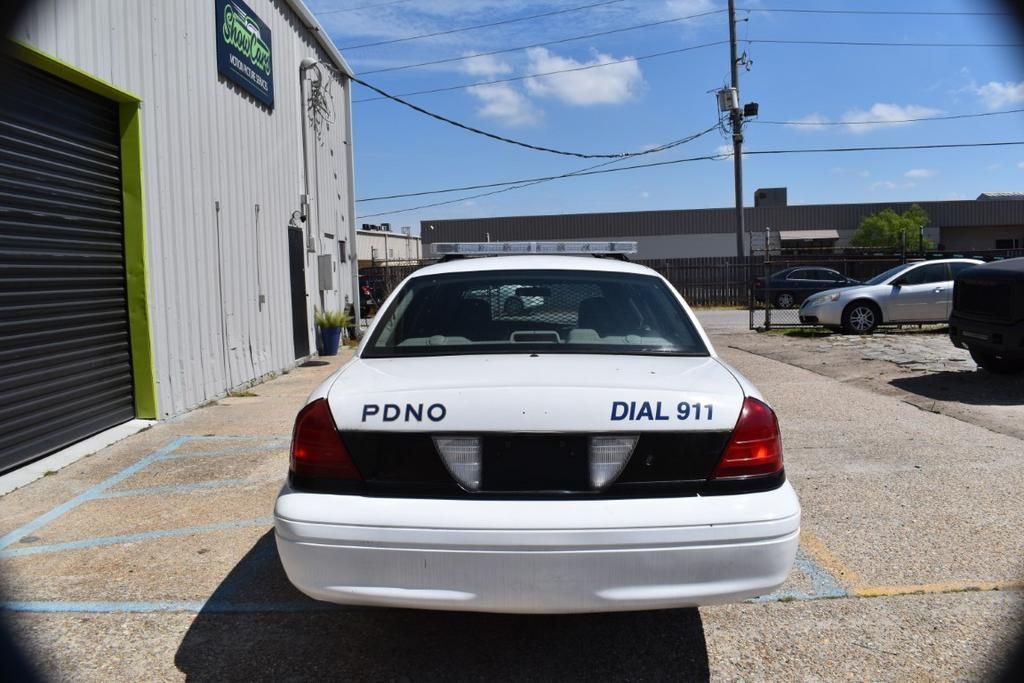 A white police car is parked in a parking lot in front of a building.