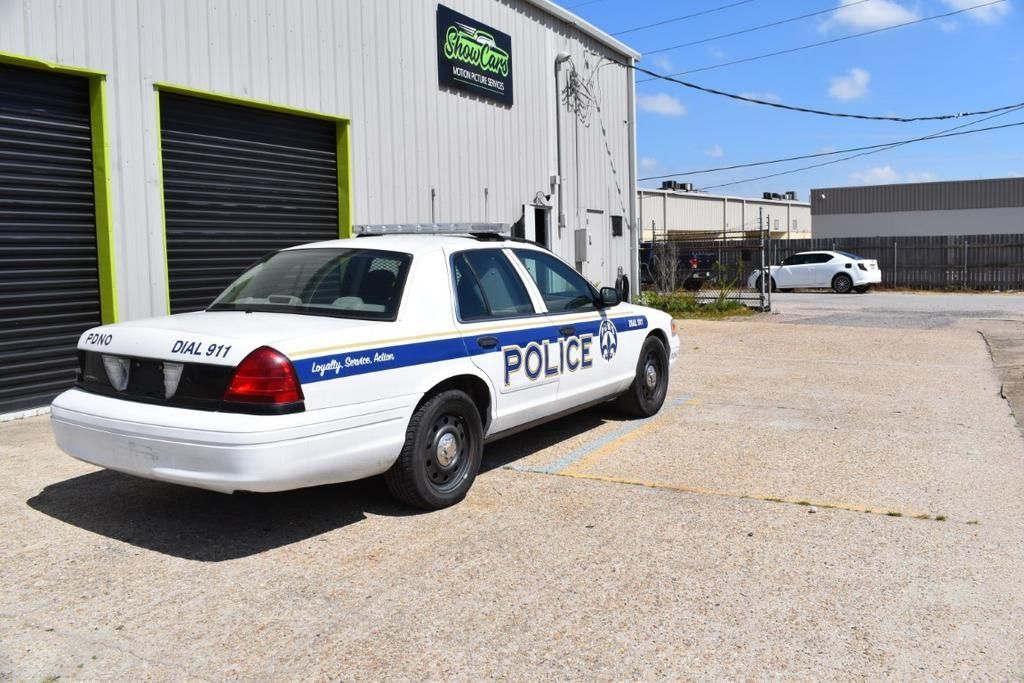 A white police car is parked in front of a building.