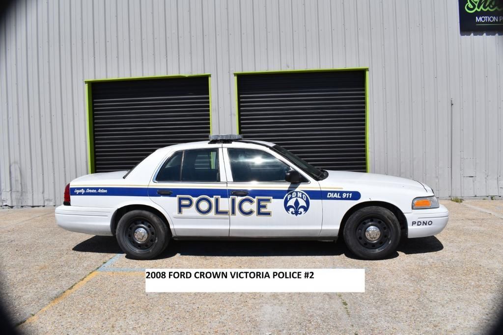 A white police car is parked in front of a building