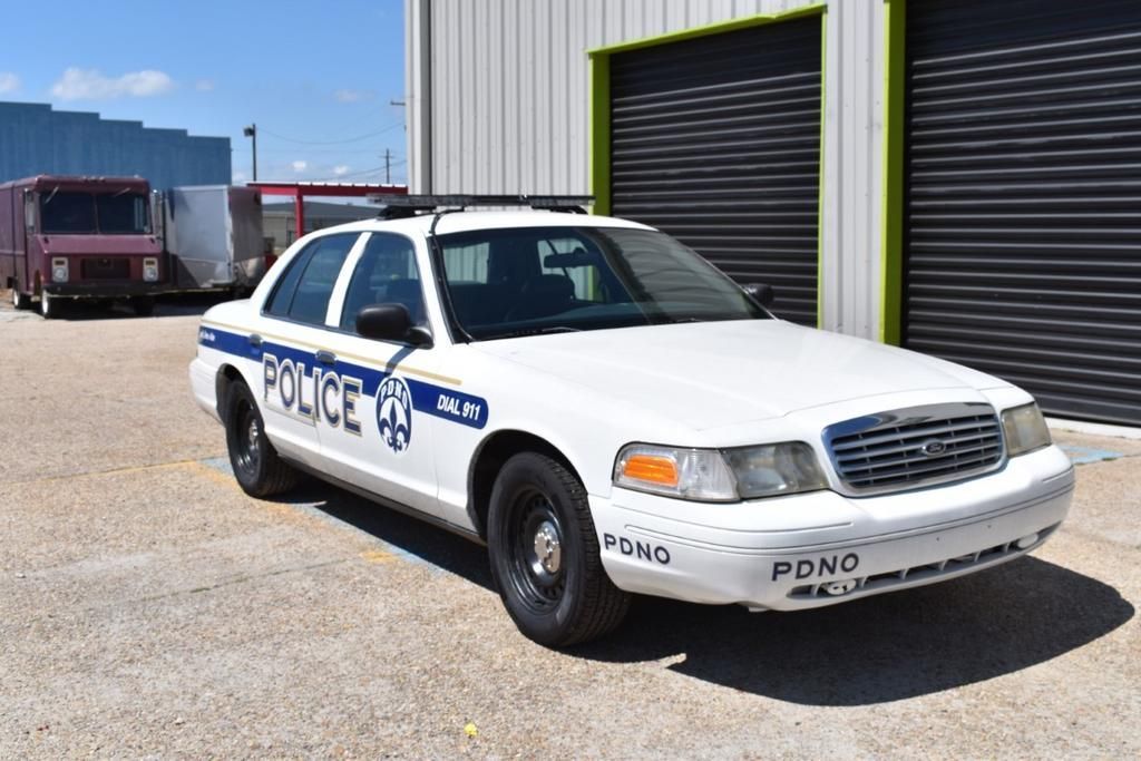 A white police car is parked in front of a building.