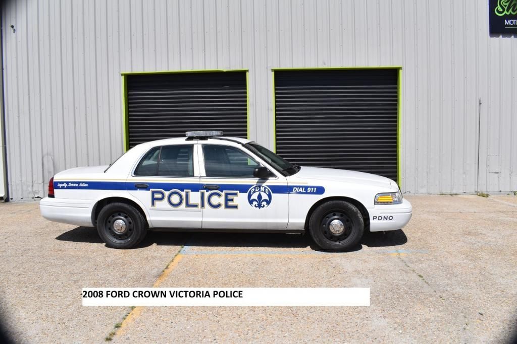 A white police car is parked in front of a building
