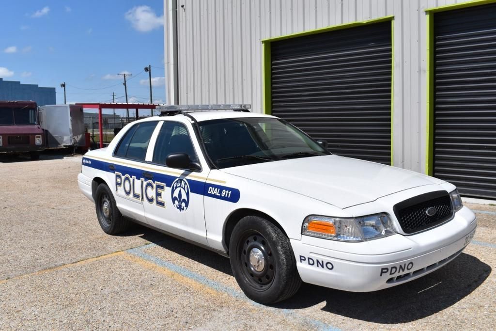 A white police car is parked in front of a building.