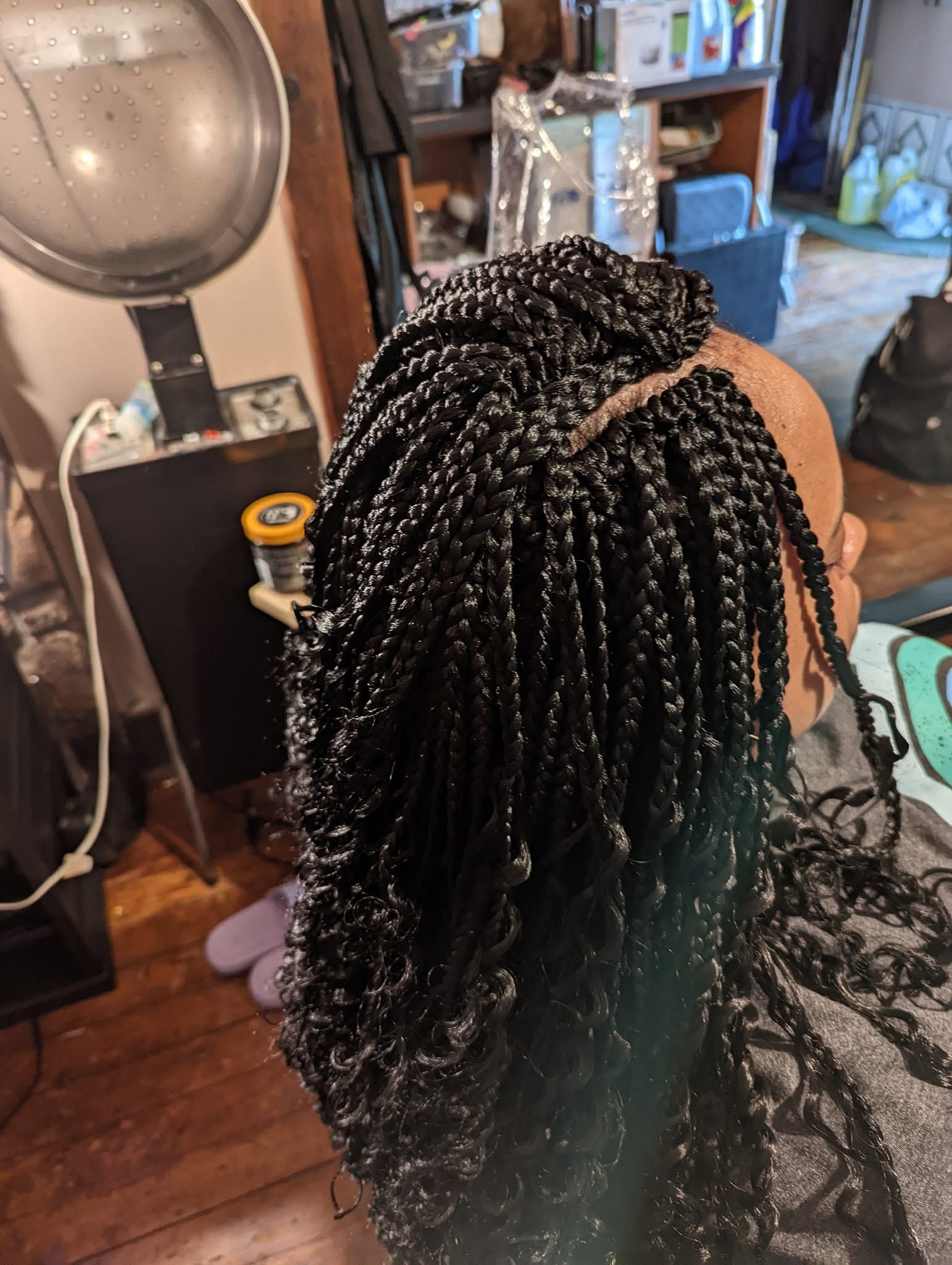 A woman is getting her hair braided in a salon.