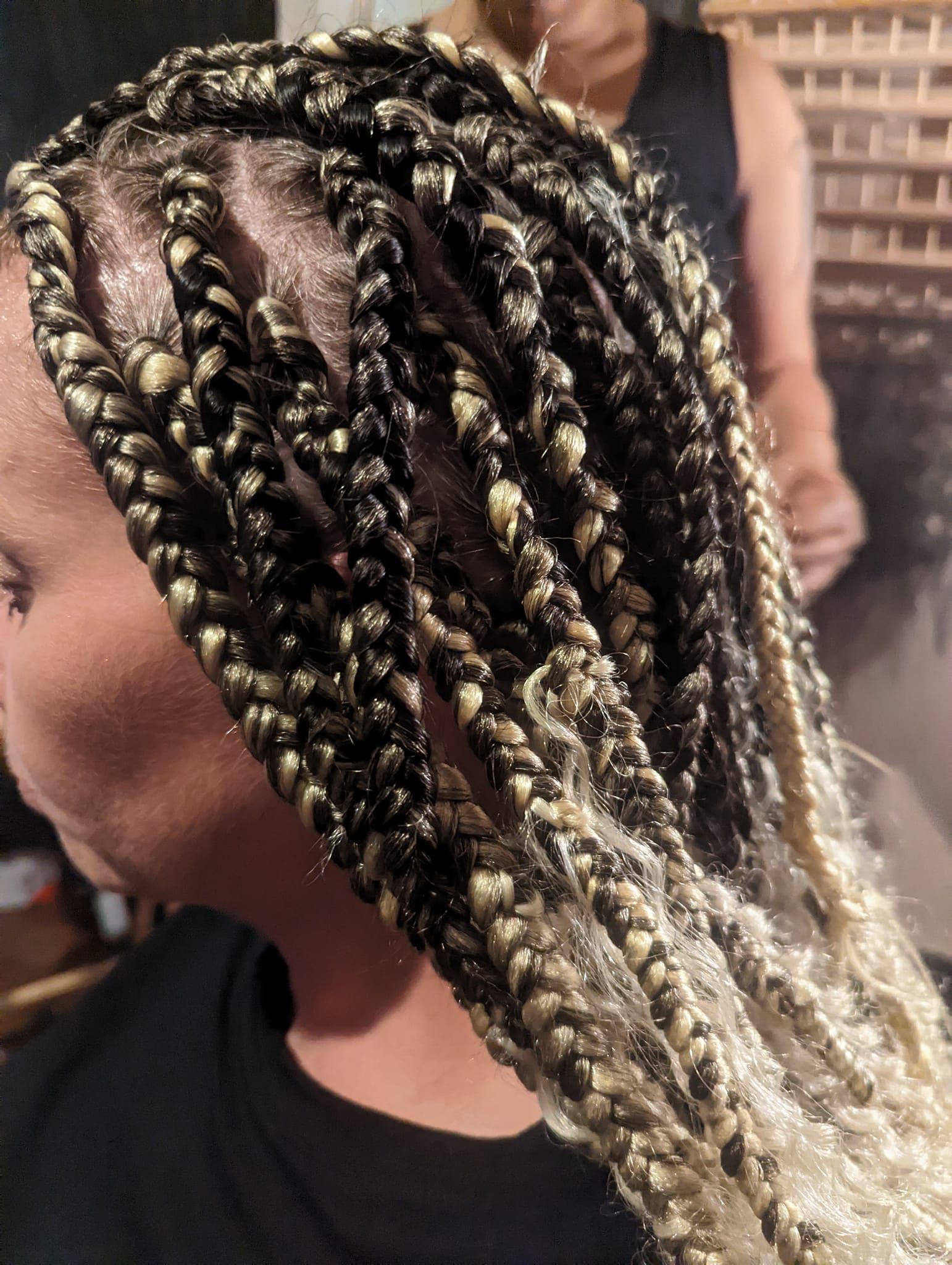 A woman with braids in her hair is wearing a black shirt.