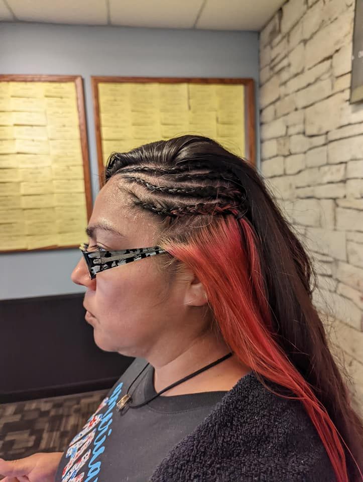 A woman with red hair and braids is wearing sunglasses.