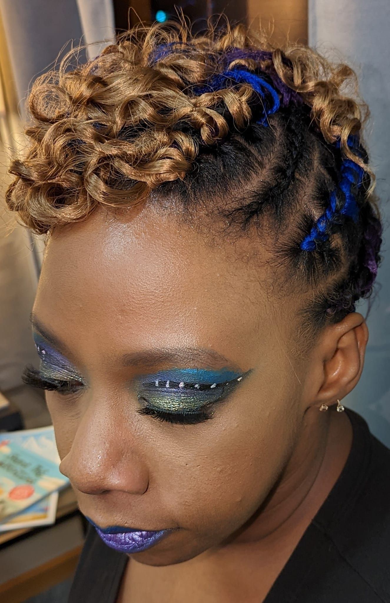 A close up of a woman 's face with blue eyeshadow and purple lips.