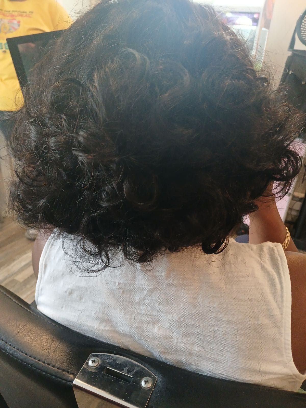 A woman with curly hair is sitting in a chair in a salon.