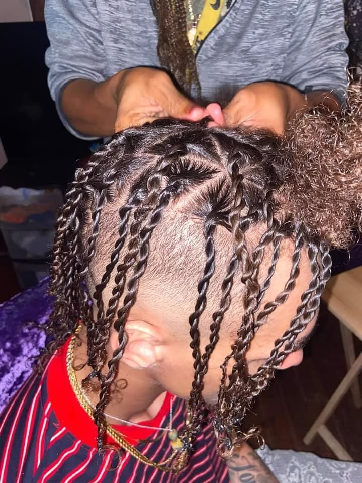 A person is braiding a child 's hair in a bun.