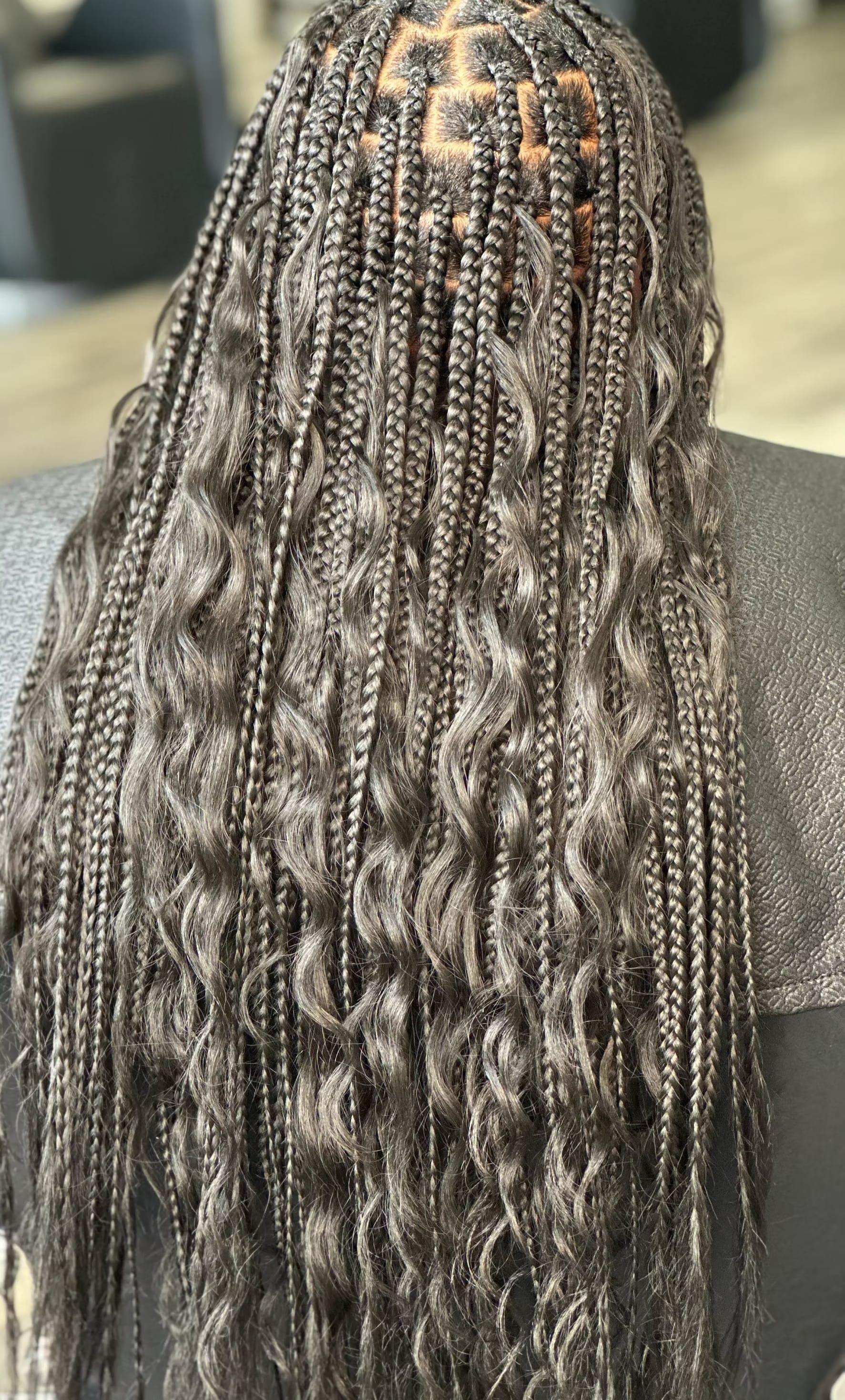 A woman with long braids is sitting on a couch in a salon.