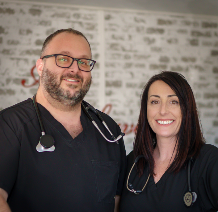 Doctor examining a child's chest with a stethoscope, parents present in a medical office setting.