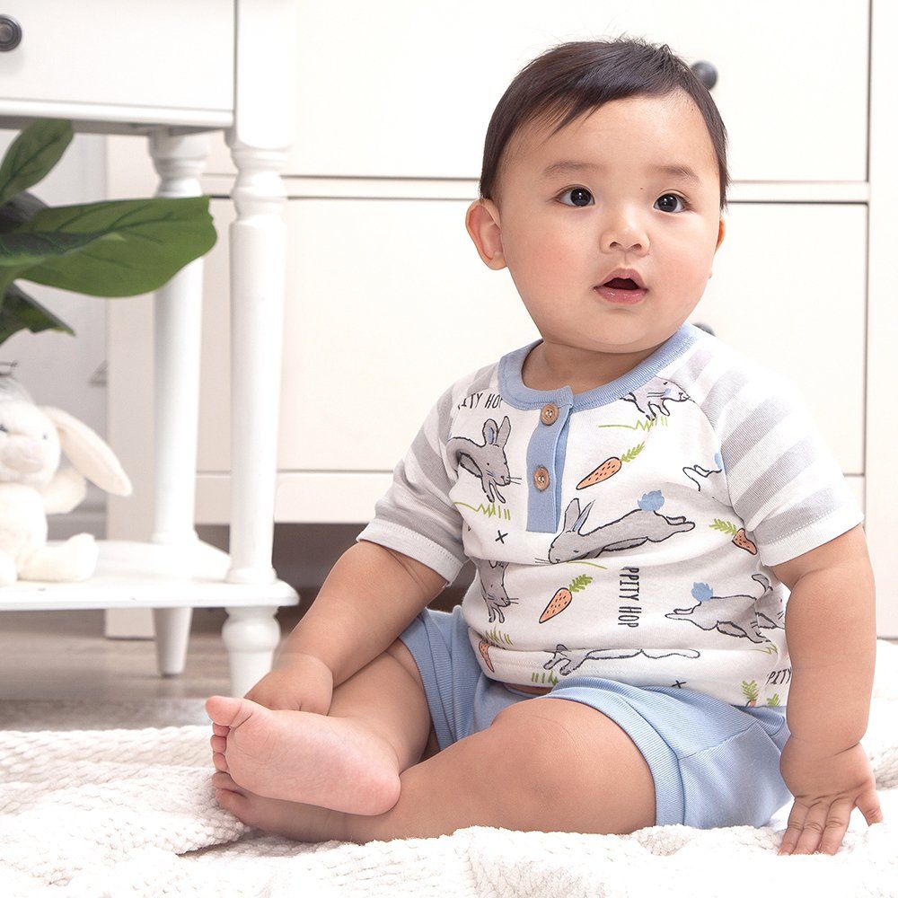 A baby is sitting on the floor with his legs crossed.