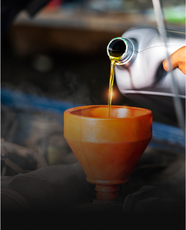 Pouring oil from a container into a funnel for a car engine.