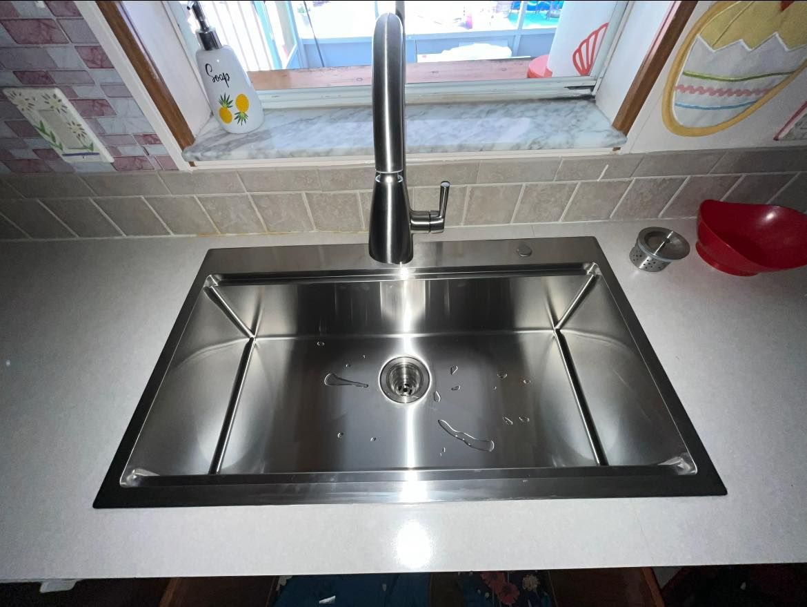 A stainless steel kitchen sink with a faucet