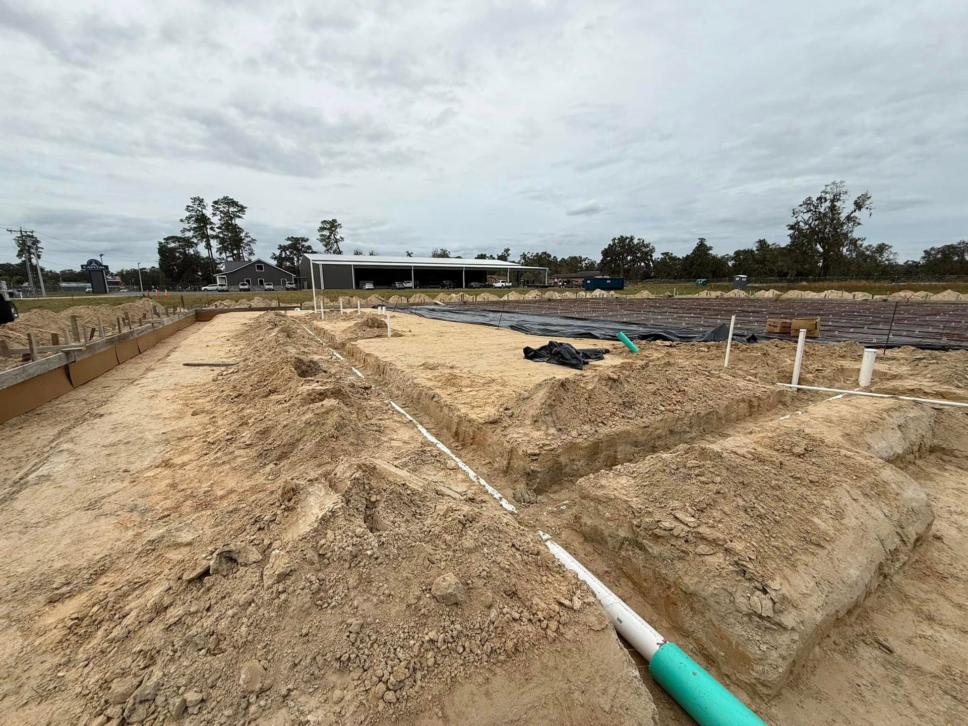 A green pipe is laying in the dirt on a construction site.