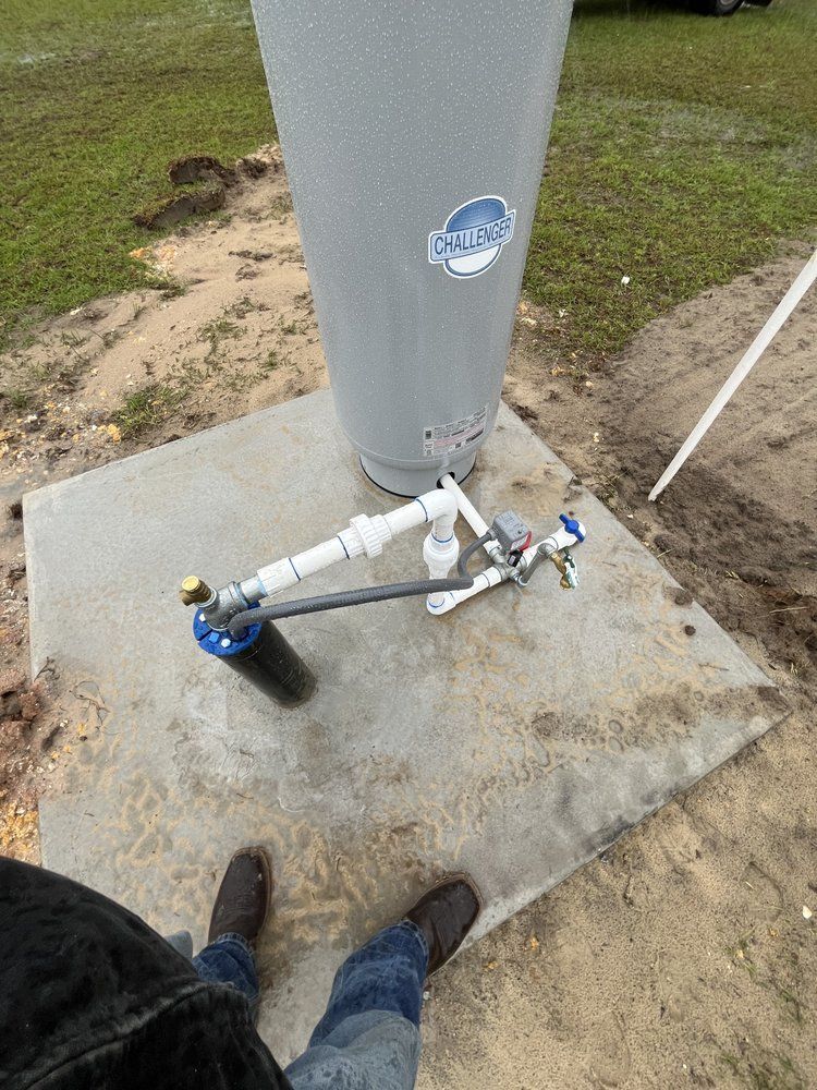 A person is standing next to a water tank with pipes attached to it.