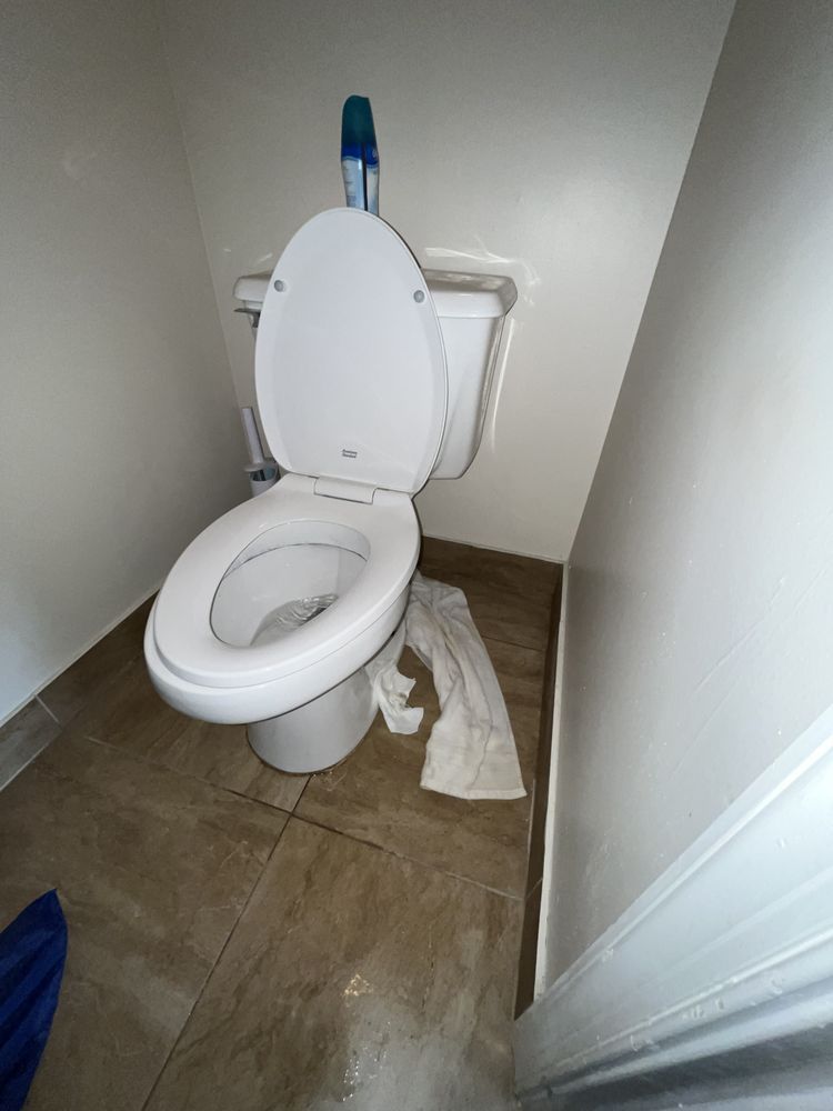 A toilet in a bathroom with a towel on the floor