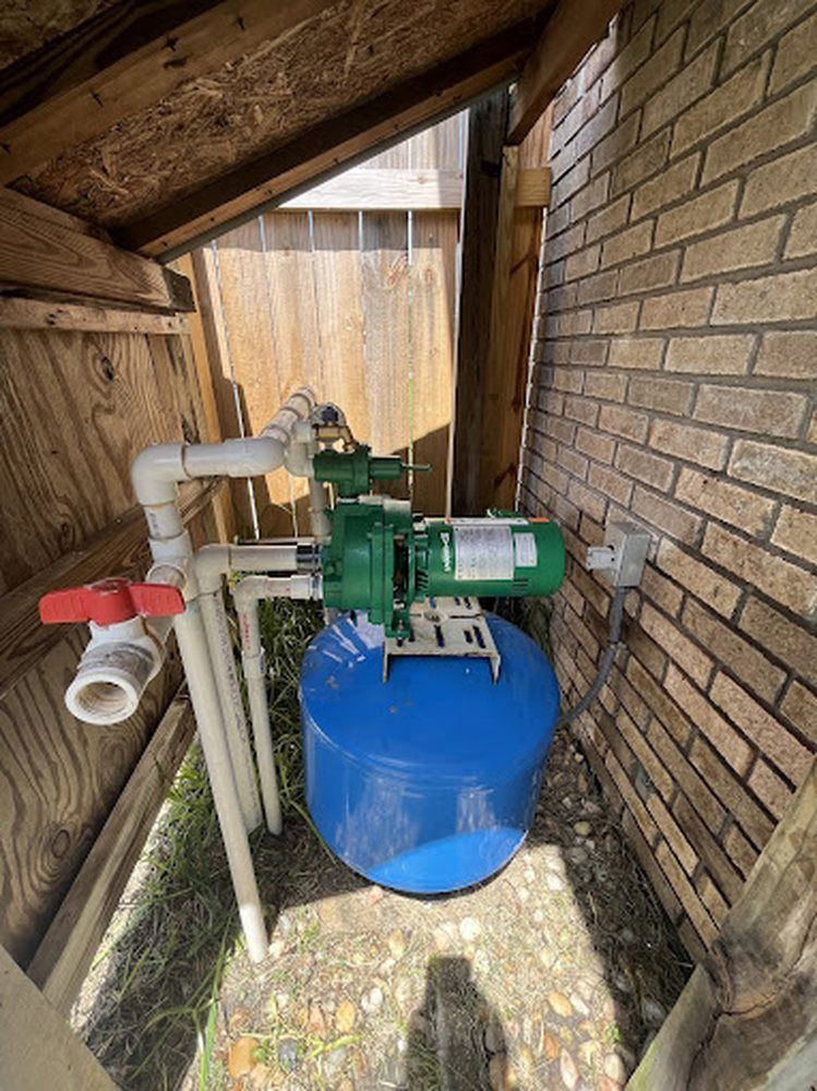 A water pump is sitting in a shed next to a brick wall.