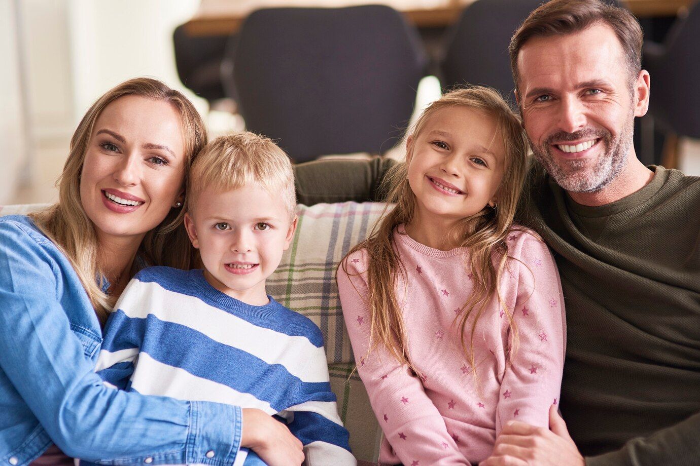 A family is posing for a picture while sitting on a couch.
